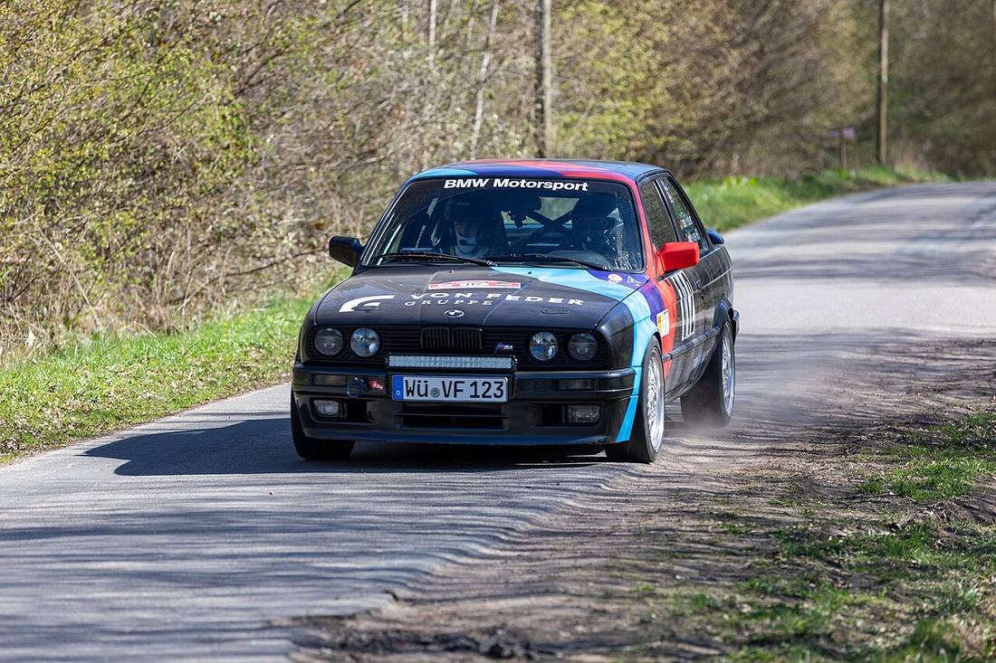 Una BMW M3 E30 nera su una strada nel bosco