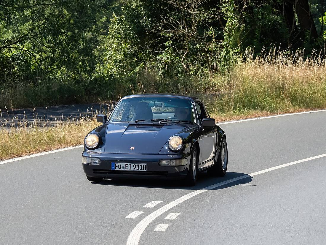Una Porsche 911 Carrera blu scuro su una strada curva