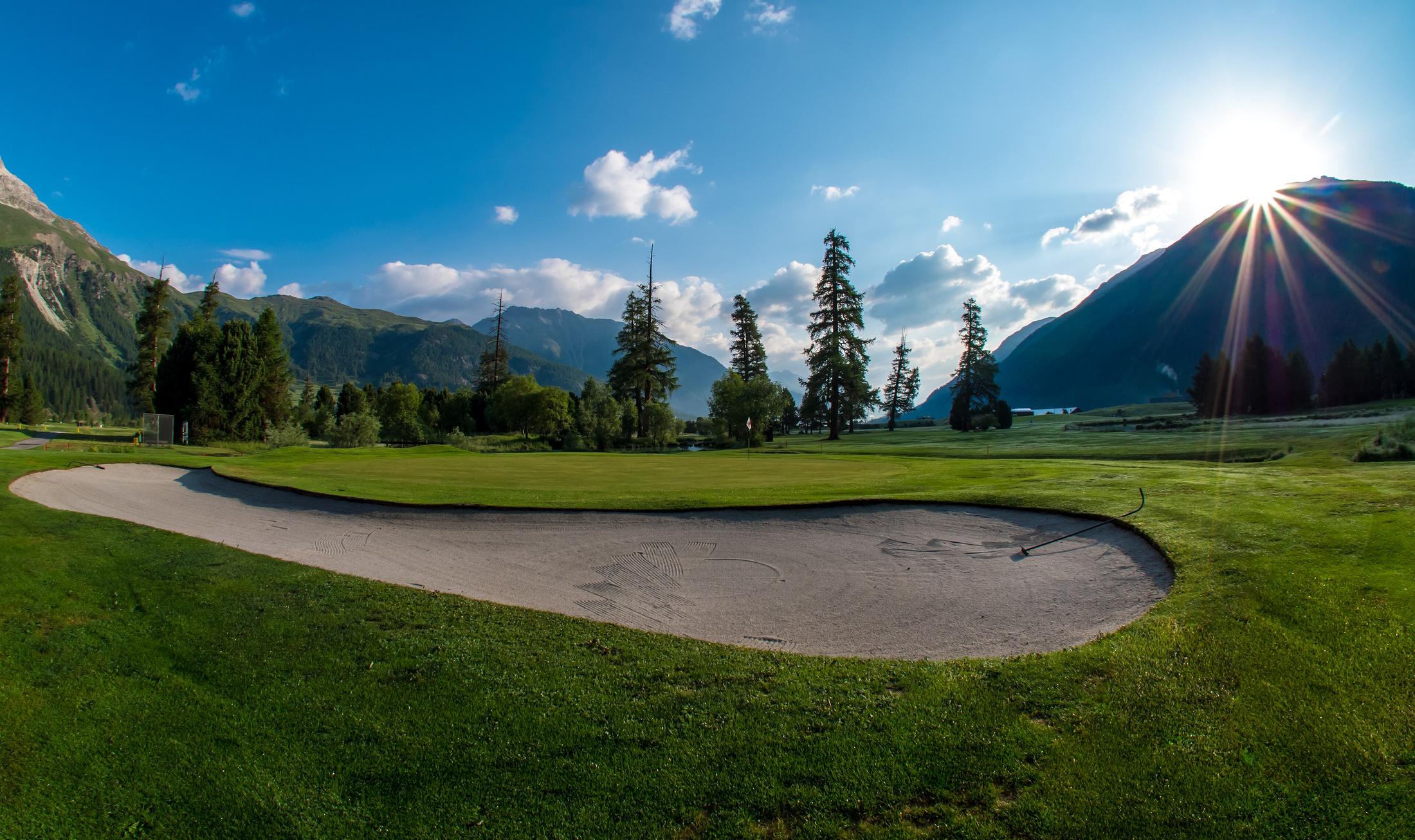 Il green dell'Engadine Golf Club al sole, tra larici e montagne
